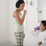 mother and child brushing teeth together